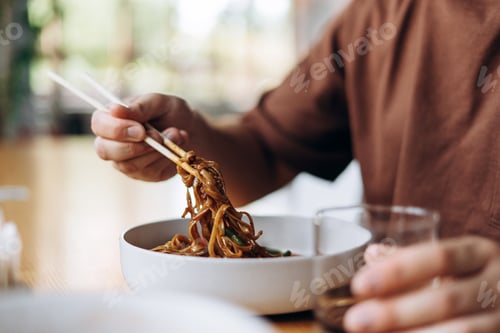 Preview: Closeup, man holding chinese chopsticks eating pasta, selective focus in hands. Food concept