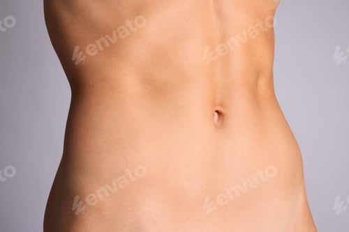 Preview: Woman with flat belly on grey background, closeup