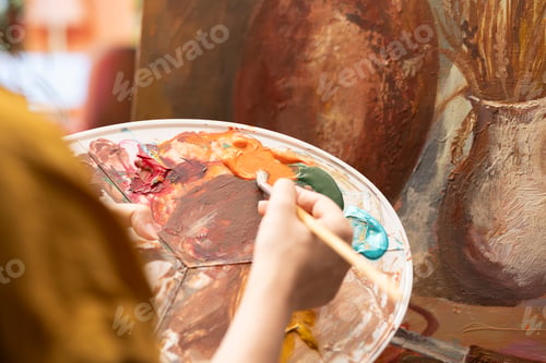 Preview: Female artist using watercolor paint and mixing colors on palette