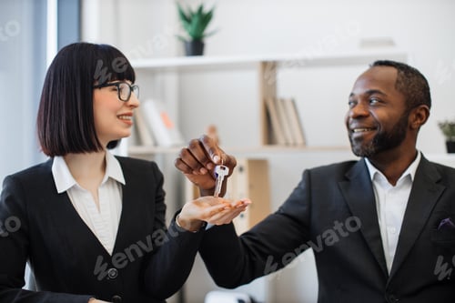 Preview: Businessman giving house keys to female coworker in agency