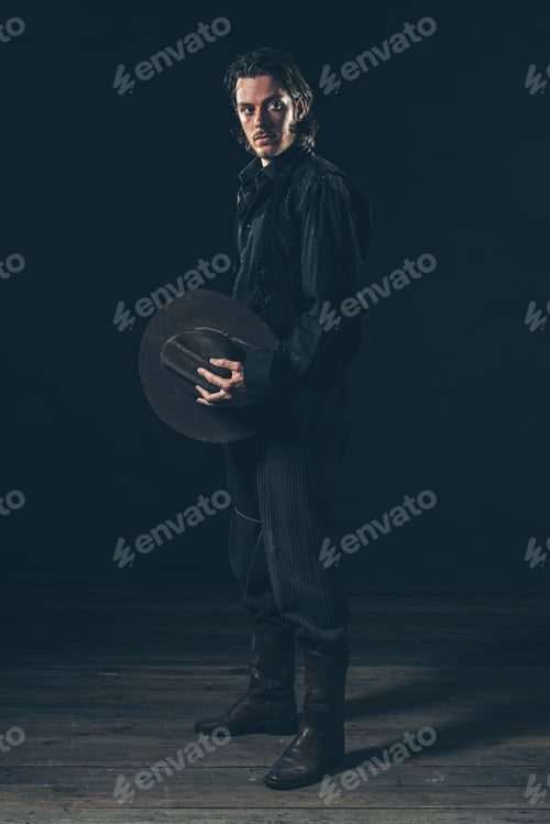 Preview: Vintage Cowboy Holding Hat In Hand. Young Man. Studio Shot.