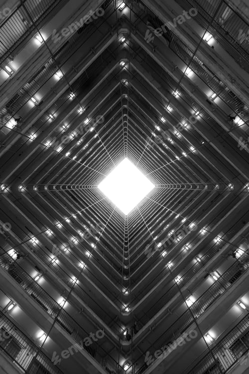 Preview: Vertical greyscale low angle shot of the light coming through the ceiling of a tall building