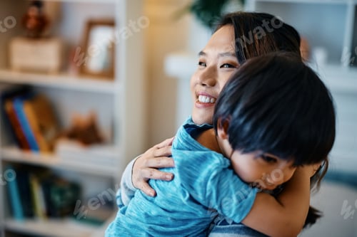 Preview: Affectionate Asian mother embracing her small son at home.