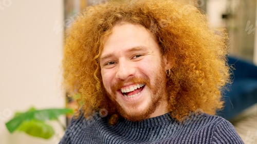 Preview: Man with curly hair smiling at camera in a coworking