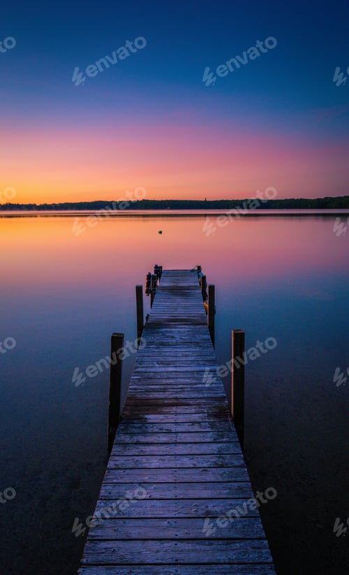 Preview: Beautiful shot of sunset colors in the horizon of a tranquil lake with a dock