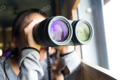 Preview: Young woman using binoculars for birdwatching