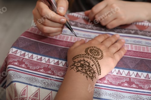 Preview: Master making henna tattoo on hand, closeup. Traditional mehndi