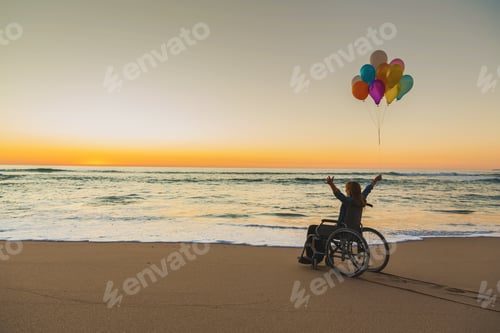 Preview: Woman in Wheelchair with Balloons on Beach at Sunset