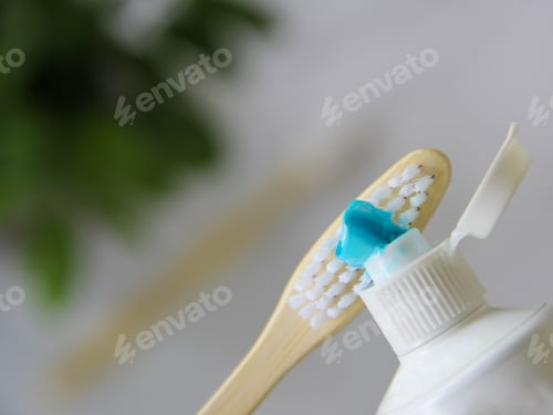 Preview: Person putting toothpaste on compostable natural wooden biodegradable ecofriendly bamboo toothbrush