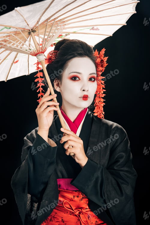 Preview: beautiful geisha in kimono with red flowers in hair holding traditional asian umbrella isolated on