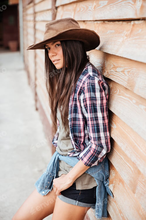 Preview: Beautiful young woman cowgirl in hat and plaid shirt