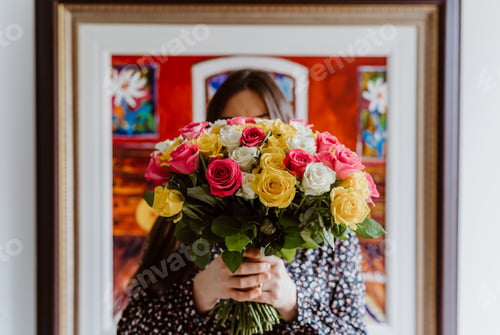 Preview: Portrait without face. Girl hiding face behind bright colorful roses flowers bouquet.