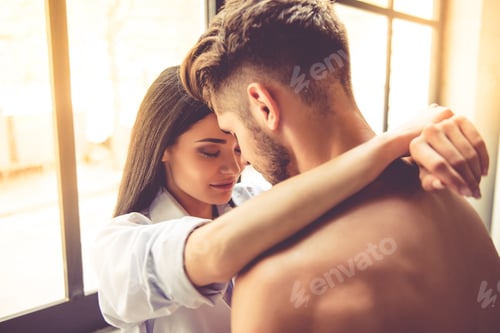 Affectionate Couple Embracing in Window Light Indoors