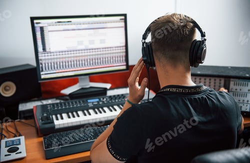 Preview: Sound engineer in headphones working and mixing music indoors in the studio