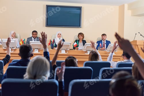 Preview: Audience in armchairs raising their hands to ask questions