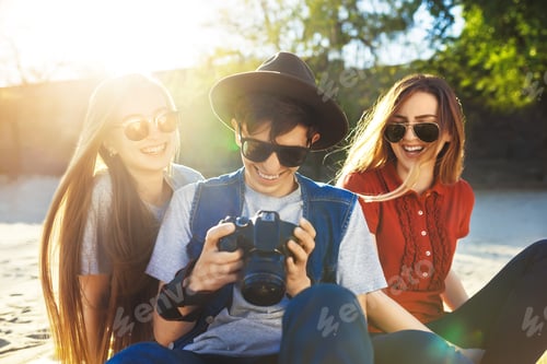 Preview: A group of friends enjoying time on the beach. They laugh and smile. Friendly atmosphere.