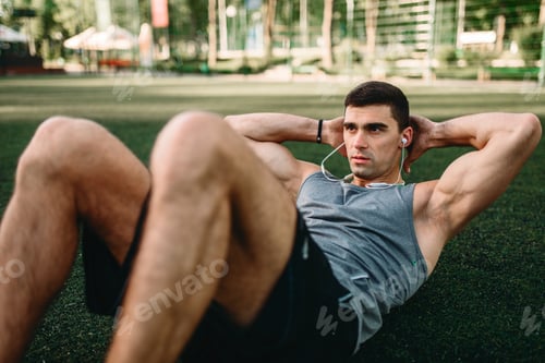 Preview: Male athlete doing exercises on the press outdoor