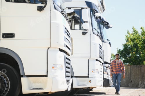 Preview: Front view. Young african truck driver is with his vehicle at daytime