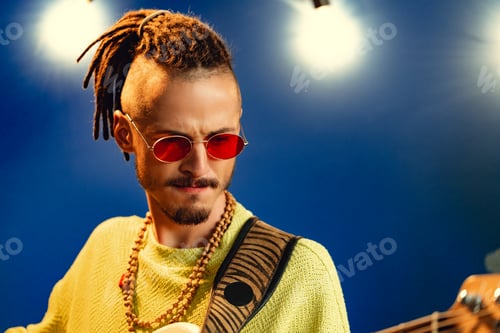 Preview: Portrait of a positive handsome caucasian guy with dreadlocks against blue background