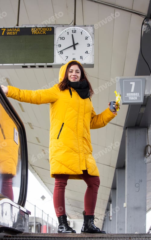 Preview: Millennial girl under the clock at the train station platform smiles