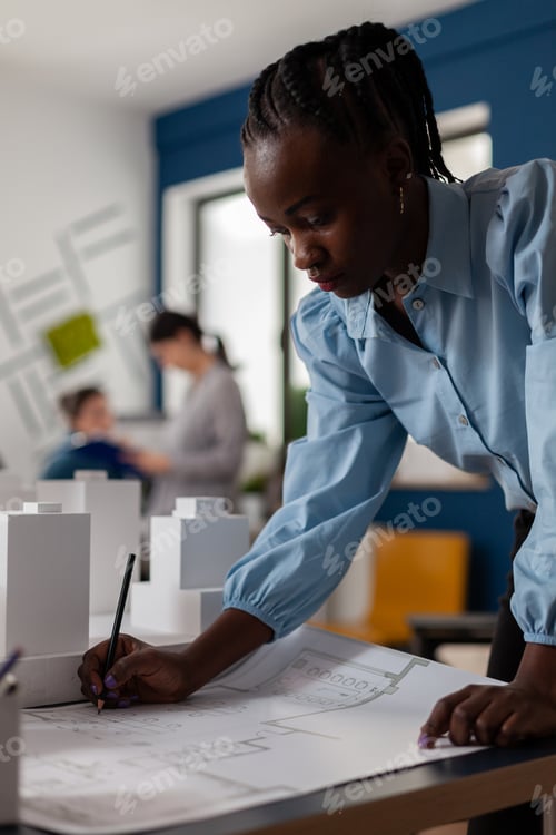 Preview: Portrait of architect making notes on construction plan papers at desk