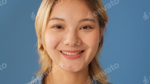 Preview: Portrait of smiling woman looks at camera isolated on blue background in studio