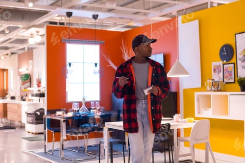 Preview: Black ethnic man shopping in a furniture store, looking at dining rooms