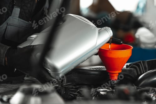 Preview: Close up of car service worker pouring new oil into car engine