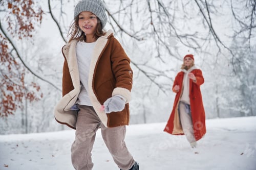 Preview: Girl is running, front view. Mother and her daughter is on the winter meadow and forest