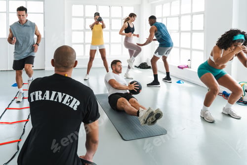 Preview: Trainer supervising athletes doing functional training workout at gym