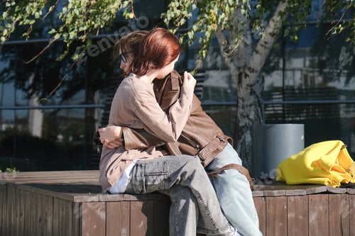 Preview: girl and mother sitting on a park bench hugging
