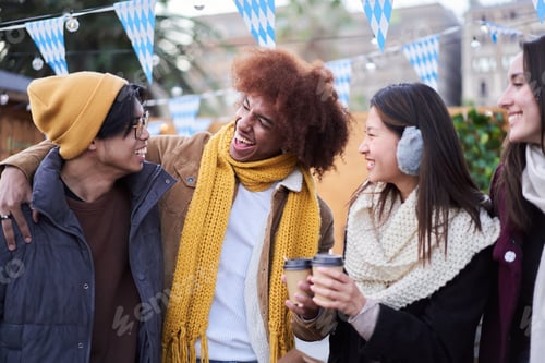 Preview: Laughing friends drinking hot beverages together street outdoors. Generation z joyful group people.