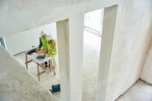 Preview: Realtor points foreman to laptop on table next to blueprints