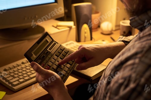 Preview: Middle Aged Man Using Calculator While Working at Desk in Office