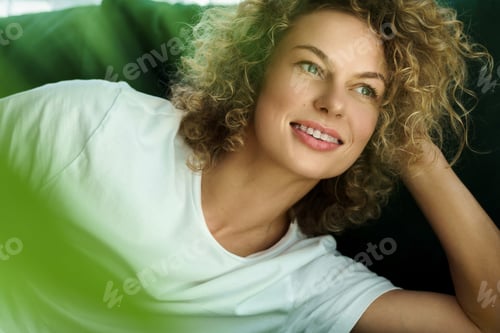 Preview: Beautiful woman with curly hair lying on green sofa
