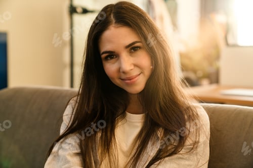Preview: Close up of a smiling young woman sitting on a couch
