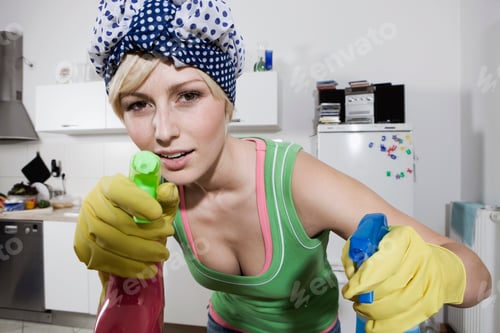Preview: Germany, Berlin, Young woman in kitchen holding spray bottles, portrait, close-up