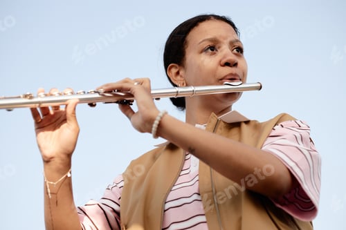 Preview: Young Adult Woman Playing Flute Outdoors during Daytime