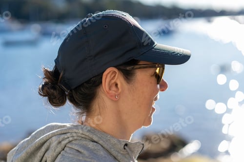 Preview: Side view portrait of happy lady wearing a hat and sunglasses and active gear. On morning walk.