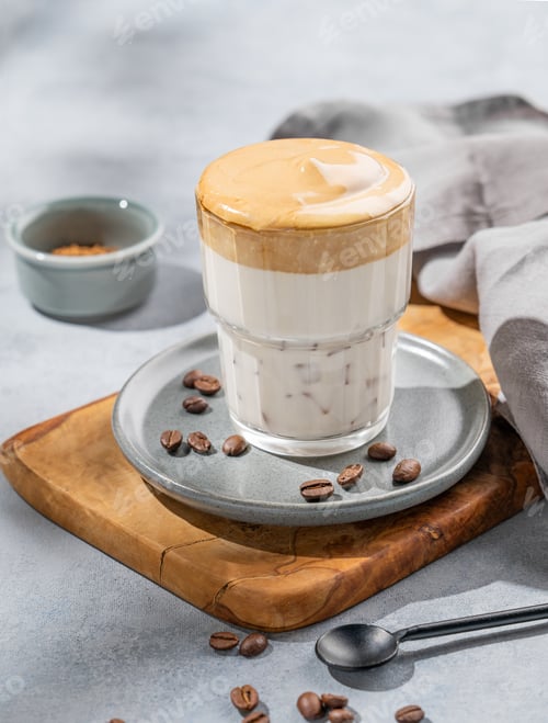Preview: Dalgona coffee. Whipped instant coffee in a glass on a wooden board with coffee beans