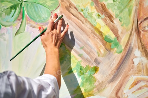 Preview: Girl artist hand holds paintbrush and draws green nature landscape on canvas