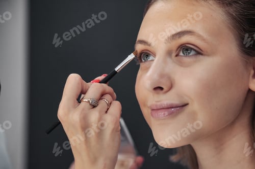 Preview: Female makeup artist makes up cute young woman in beauty salon