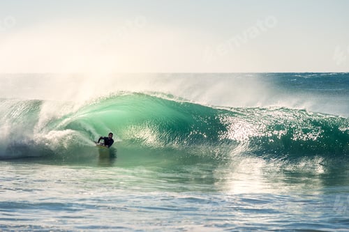 Preview: man surfing the barrel of a wave at sunset