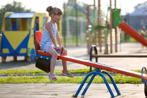 Preview: Cute young child girl outdoors on see-saw swing on sunny summer day.
