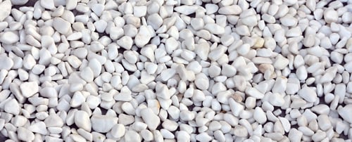 Preview: A lot of round and oval stones of white color lie on the ground in the garden
