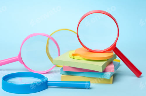 Preview: Multicolored plastic magnifying glasses on a blue background and paper notes