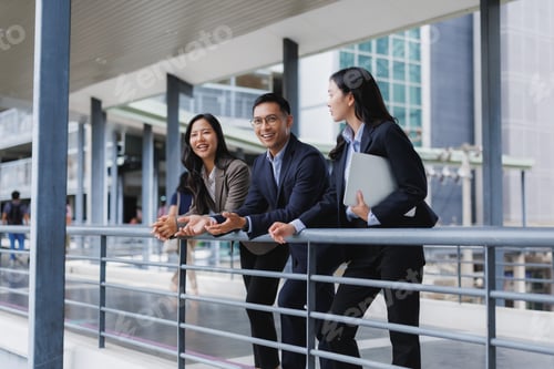 Preview: Business people talking and leaning on railing in modern office building