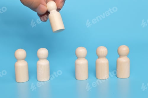 Preview: Hand grabs wooden doll figure from the group of workers. Firing someone concept.