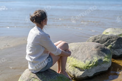 Preview: Woman sitting near sea, looking to water