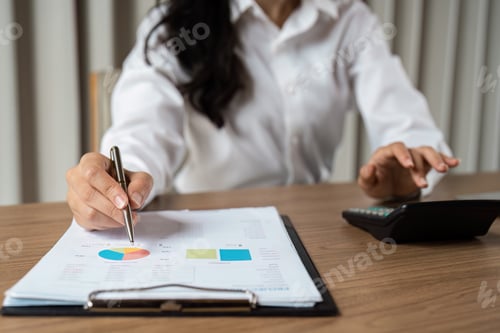 Preview: Businesswoman Analyzing Financial Data with Charts and Calculator in Modern Office Setting for